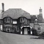 The Jubilee Inn, now the Odd Wheel, as it was in the late 1940s, and in reality little different to its appearance in 1900. The pub provided a focus in the eastern part of the parish, and for several decades in the mid-twentieth century was run by members of the Perring family. The left hand edge of the roof shows signs of repair due to it being damaged by a cattle lorry attempting to get down to West Wembury Farm.  The road was very narrow until widening in 1958, as can be seen by the hedge on the extreme left of the photograph.  