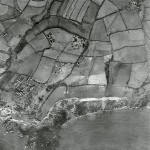 Wembury Point dominates the south west of the photo. Numerous war-related buildings on the Point were the precursors of the post-war naval gunnery school, HMS Cambridge. The semi-circular feature to the north is a major anti-aircraft battery. In the farm landscape, the outlines of medieval strip fields survive, and part of Langdon is visible in the north east. 
